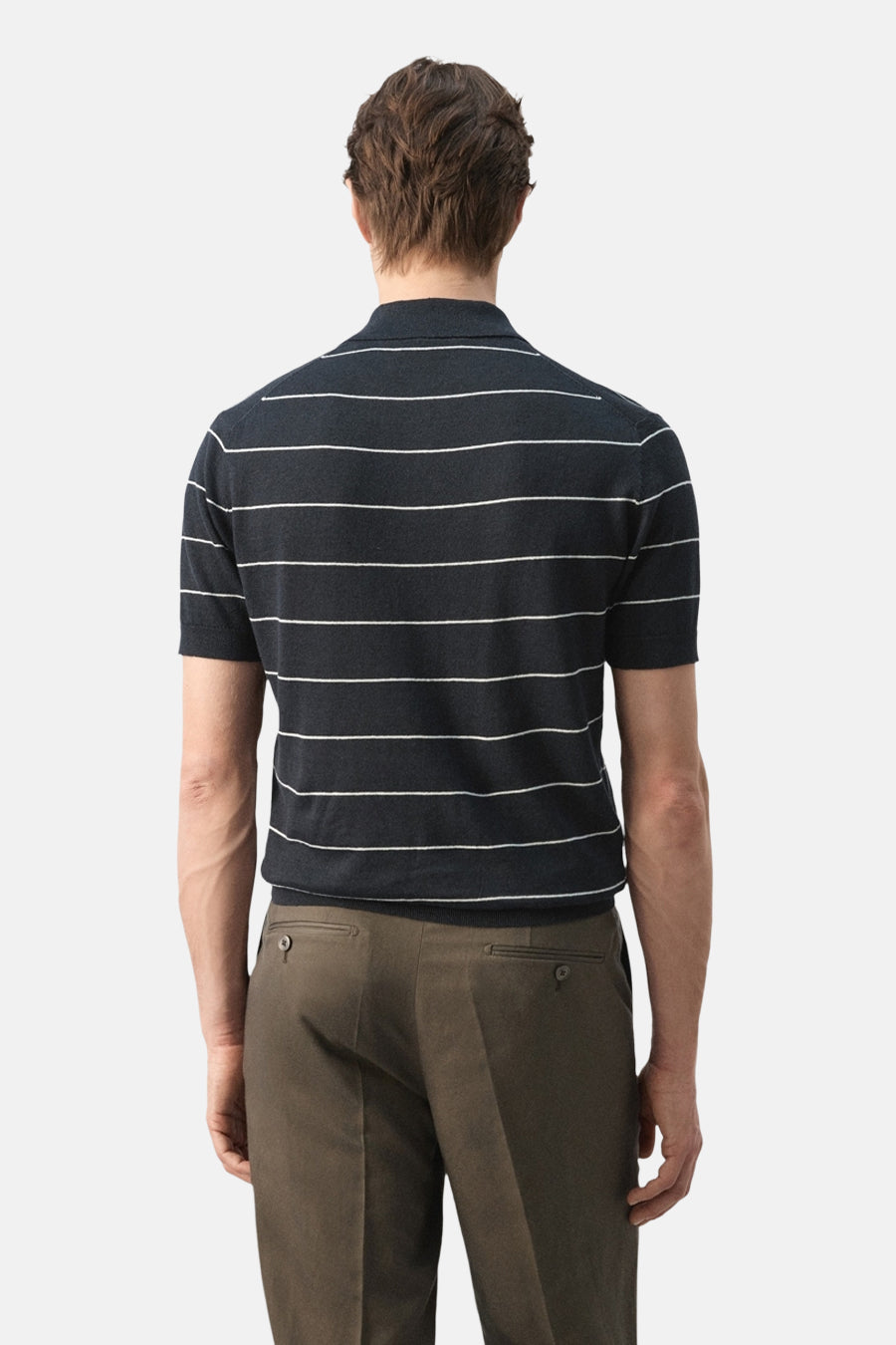 Zwarte polo van MANGO met gestreepte patroon, gedragen met olijfgroene pantalon, achteraanzicht.
