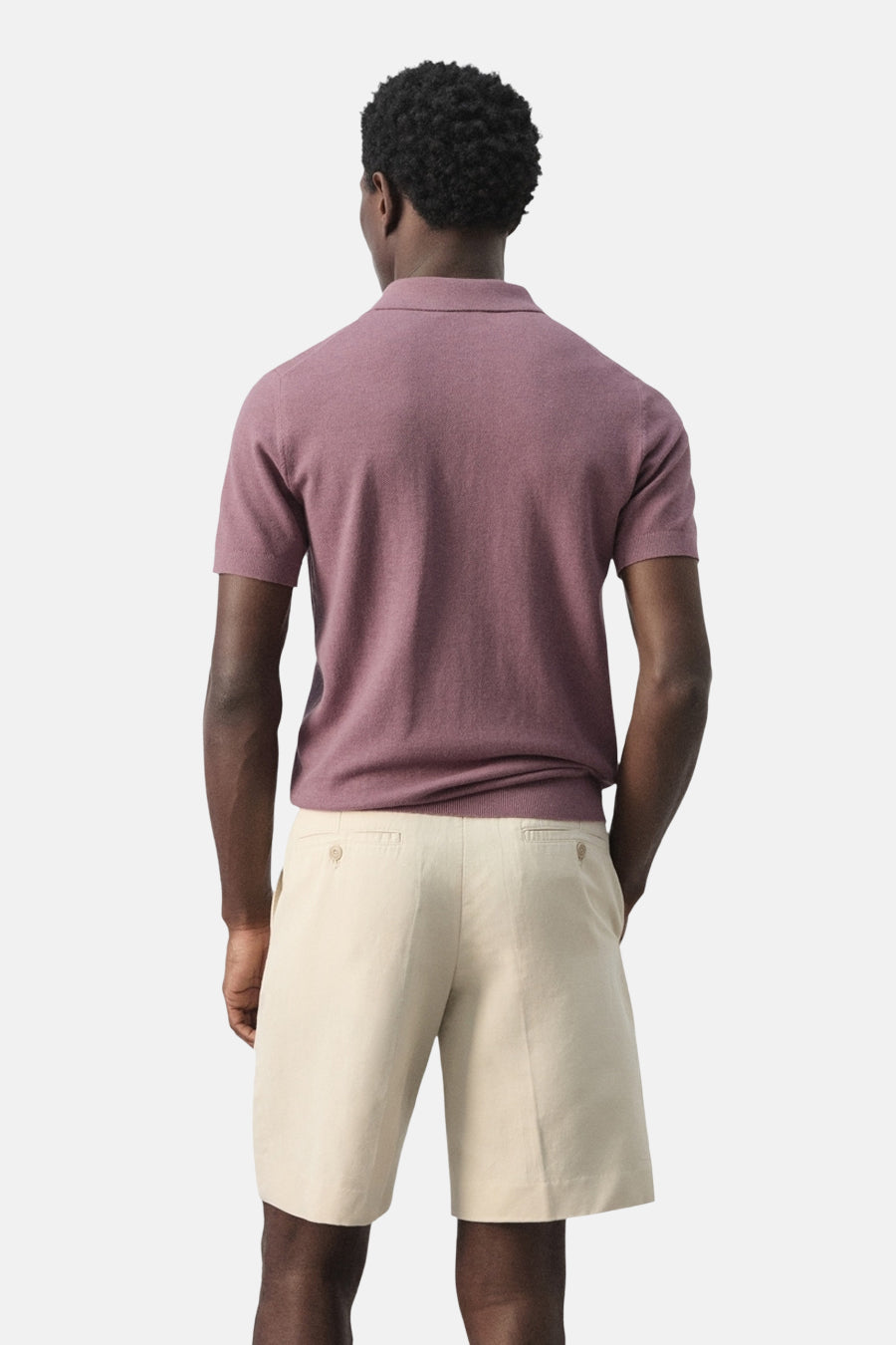 Paarse polo van MANGO, gezien van achteren, gecombineerd met beige shorts.