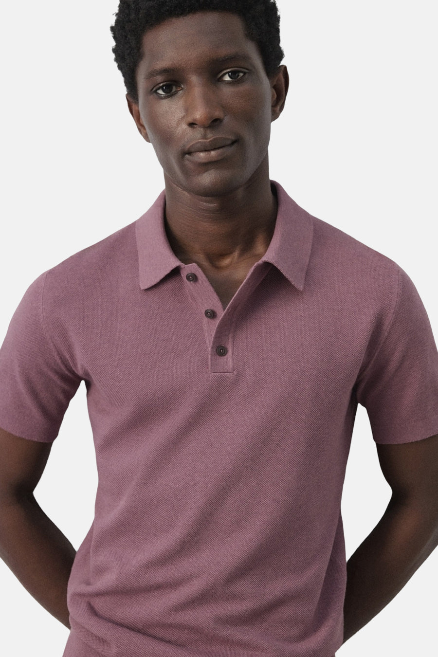 Paarse polo van MANGO, met korte mouwen en knoopsluiting, getoond op een model tegen een effen achtergrond.
