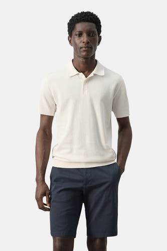 Ecru polo van MANGO, met korte mouwen en gedragen met blauwe shorts.
