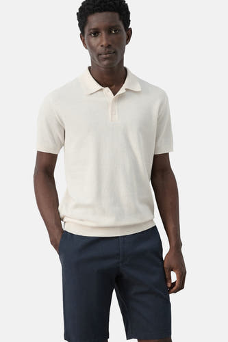 Ecru polo van MANGO, met korte mouwen en gedragen met marineblauwe shorts.

