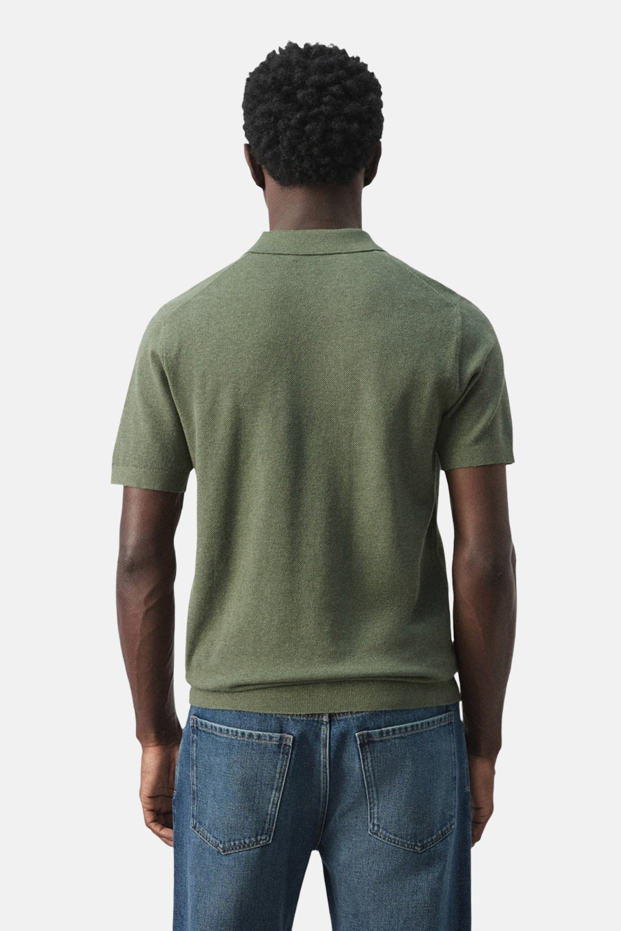 Groene polo van MANGO, achterkant, met korte mouwen en een effen kleur. Gedragen met een jeans.