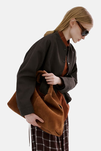 Bruine blazer van MANGO, gedragen met een oranje blouse en een geruite broek, gecombineerd met een bruine tas.