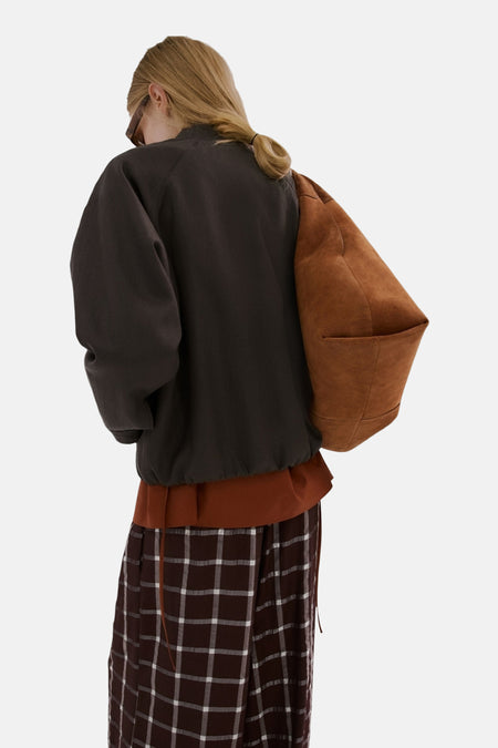 Bruine blazer van MANGO, met lange mouwen en een relaxte pasvorm, gedragen met geruite broek.

