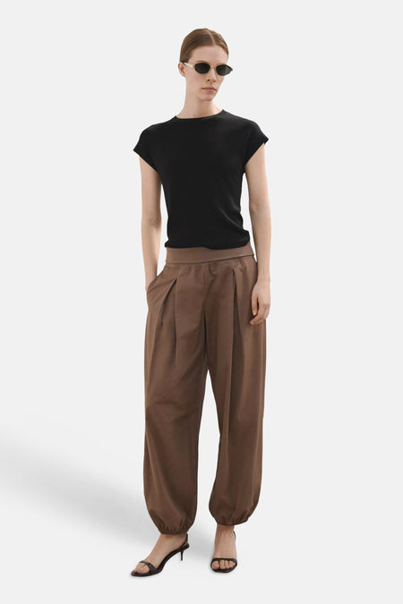 Haut noire à manches courtes de MANGO, portée avec un pantalon marron et des sandales foncées.