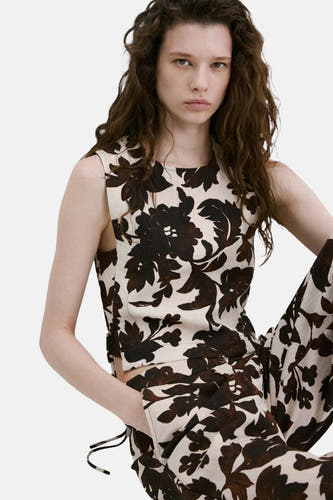 Chemisier court sans manches de couleur écru à motif floral marron foncé de MANGO, porté avec un pantalon assorti, vu de côté/arrière.