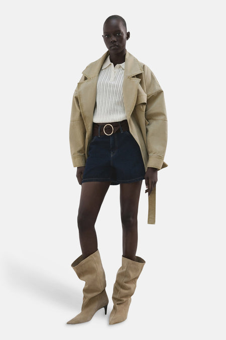 Donkerblauwe denim short van MANGO, met een bruine riem en een grote ronde gesp, gecombineerd met laarzen.