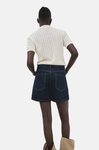 Donkerblauwe denim bermuda van MANGO, met zakken aan de achterkant en gecombineerd met een gebreide top.