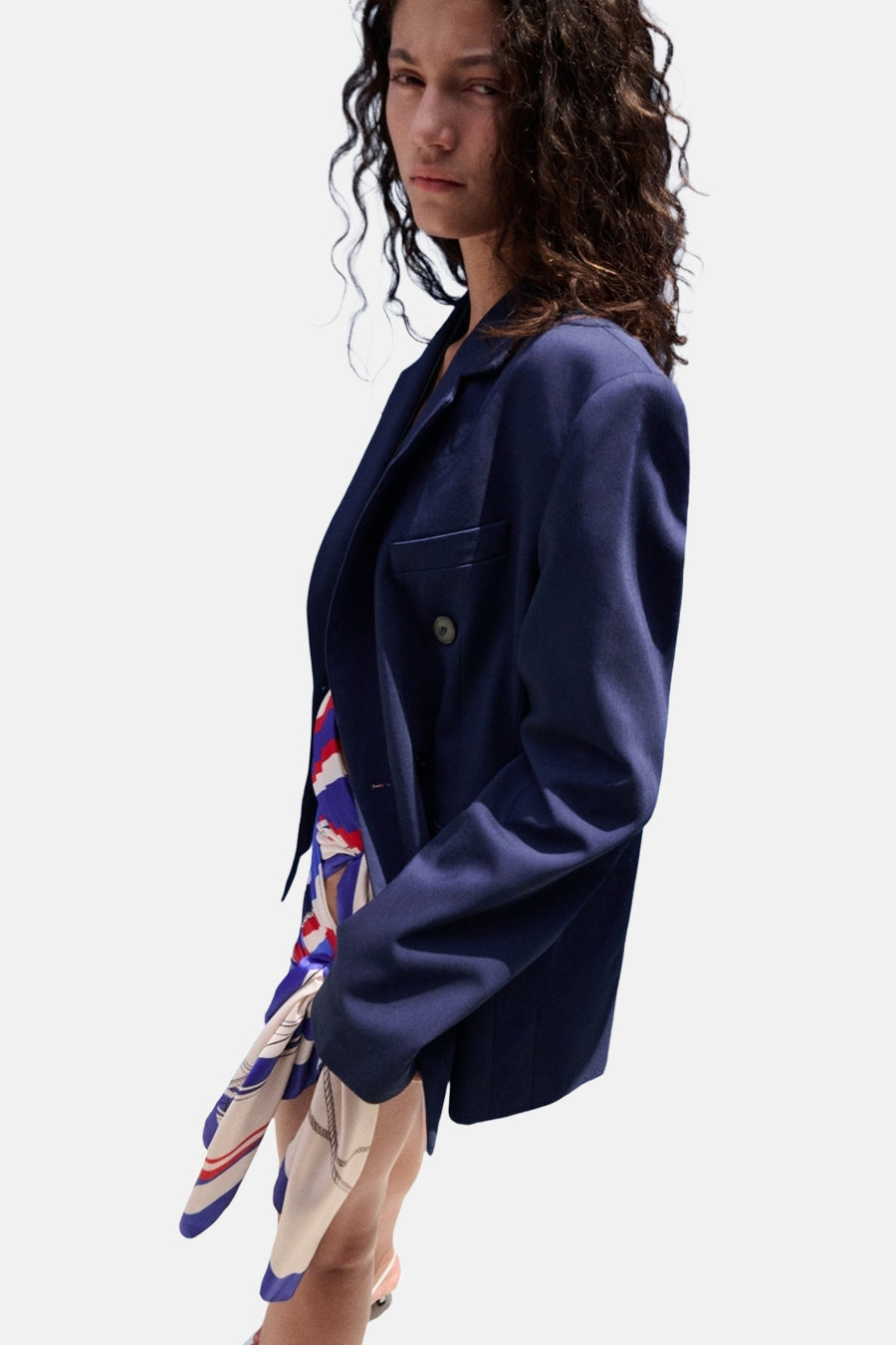 Zijwaarts zicht op een double-breasted blauwe blazer van MANGO, gedragen over een kleurrijke top met nautisch patroon.