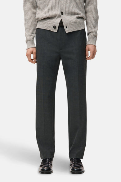 Grijze broek van MANGO, gecombineerd met een grijze cardigan en zwarte leren loafers.

