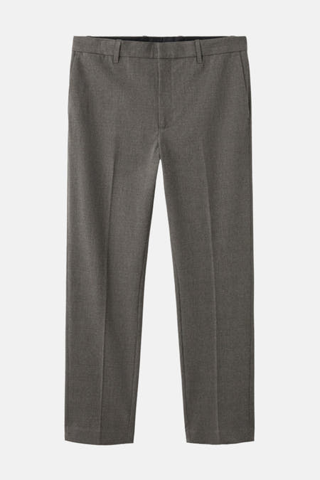 Pantalon gris de MANGO avec un tissu lisse et uniforme, des plis, sur un fond blanc.