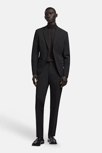 Zwarte blazer van MANGO met twee knopen, gedragen over een donkere coltrui met bijpassende pantalon en loafers.