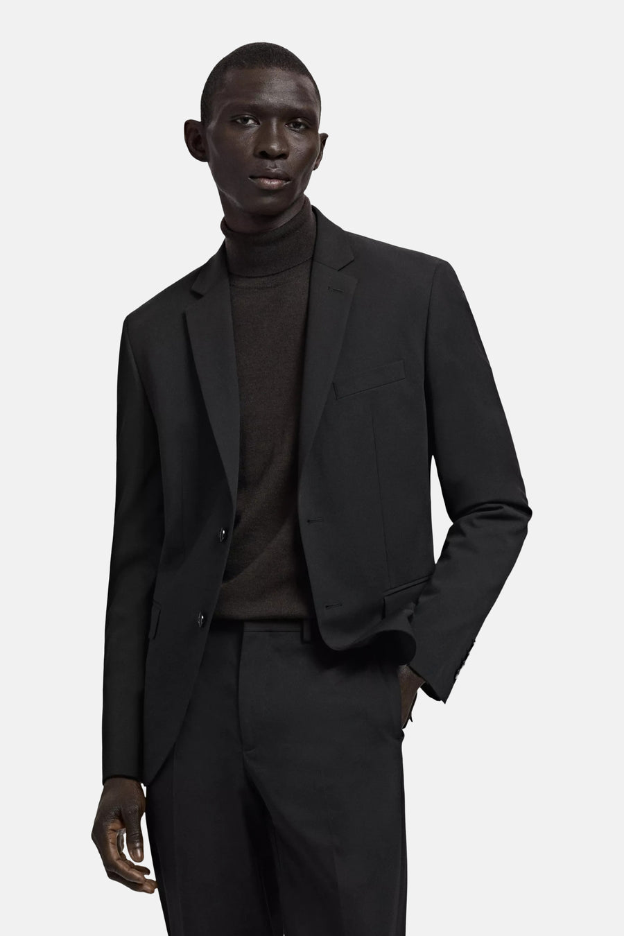 Zwarte blazer van MANGO met twee knopen en revers, gedragen over een donkere coltrui.