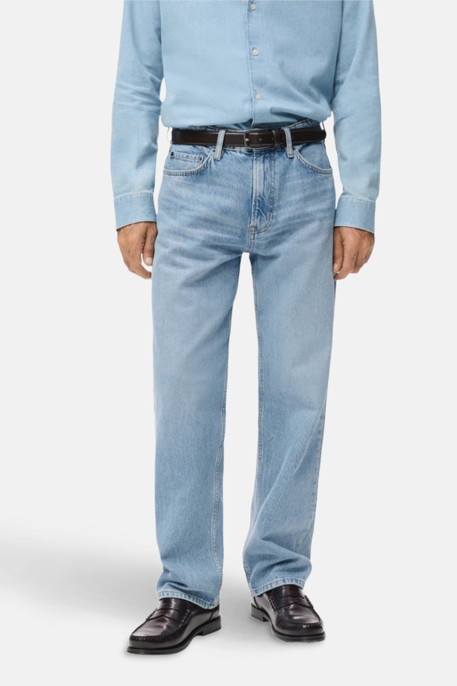 Lichtblauwe straight jeans denim van MANGO, gedragen met een blauw overhemd en bruine leren riem en loafers.
