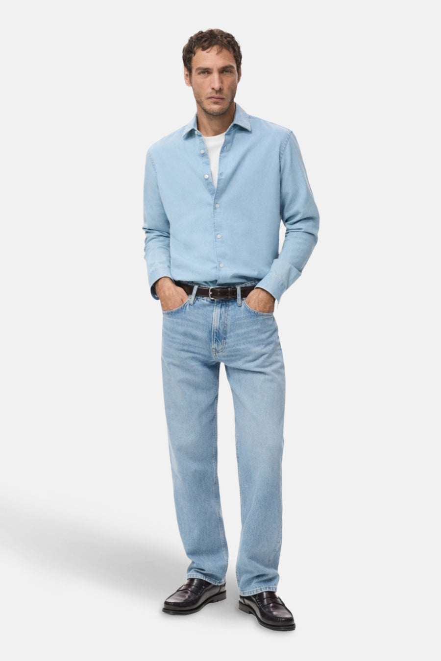 Lichtblauwe denim straight jeans van MANGO, gedragen met een bruine riem en leren loafers.