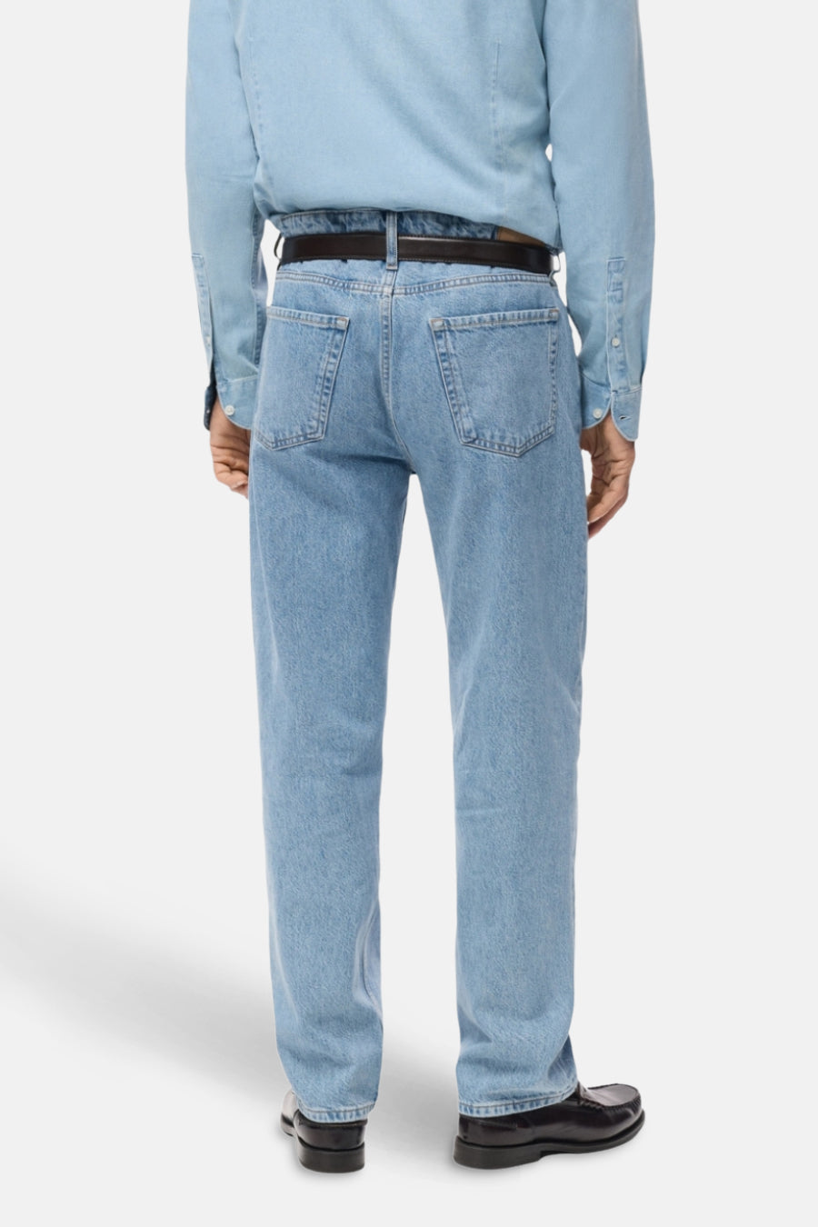 Lichtblauwe straight jeans van MANGO, gezien van achteren, met een zwarte riem en zwarte schoenen.
