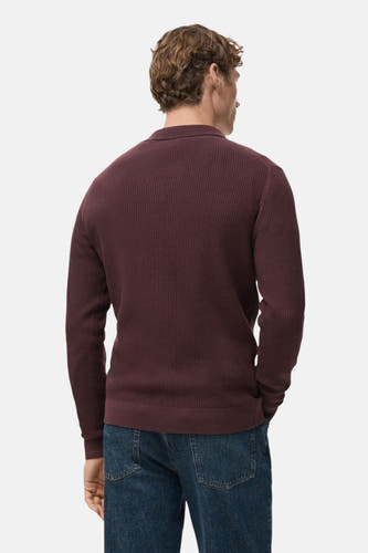 Bordeaux V-hals trui van MANGO, met fijne ribbels en gedragen met een donkerblauwe jeans.
