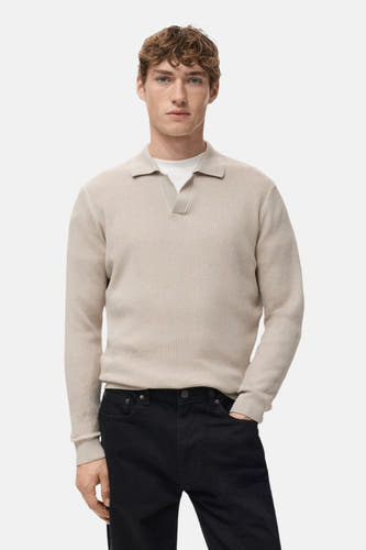 Gilet V encolle beige de MANGO, avec une texture côtelée, vu de l'arrière, associé à un pantalon noir.