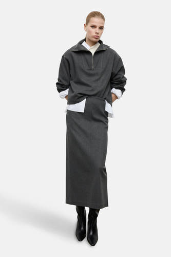 Grijze sweater van MANGO, gecombineerd met een wit overhemd en een lange, grijze rok.