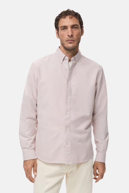 Chemise rose à manches longues de MANGO, vue de derrière, avec un pantalon crème et des chaussures noires.