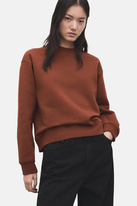 Model met bruine trui en zwarte jeans.