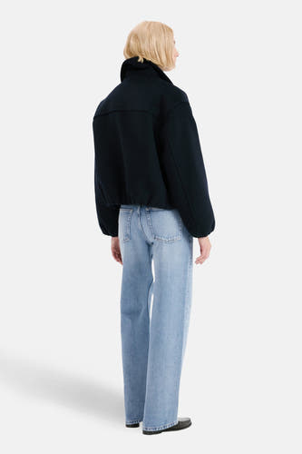 Lichtblauwe rechte jeans van MANGO, gezien van achteren, gecombineerd met een donkerblauw jasje en zwarte schoenen.