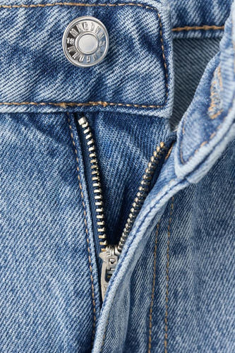 Jean en denim bleu clair droit de MANGO, avec fermeture éclair et boutons argentés.