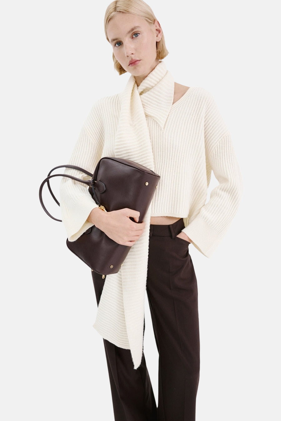 Bruine schoudertas van MANGO, gedragen met een witte trui en bruine pantalon.