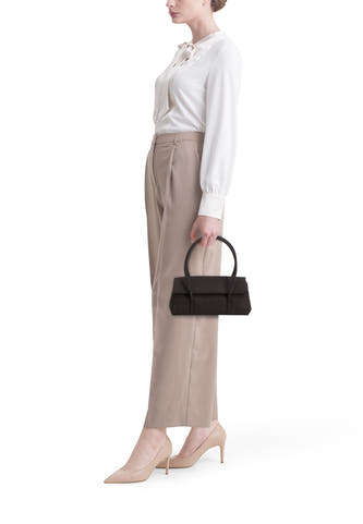Sac à bandoulière en denim bleu marine de MANGO, porté avec un pantalon beige, une blouse blanche et des talons beiges.