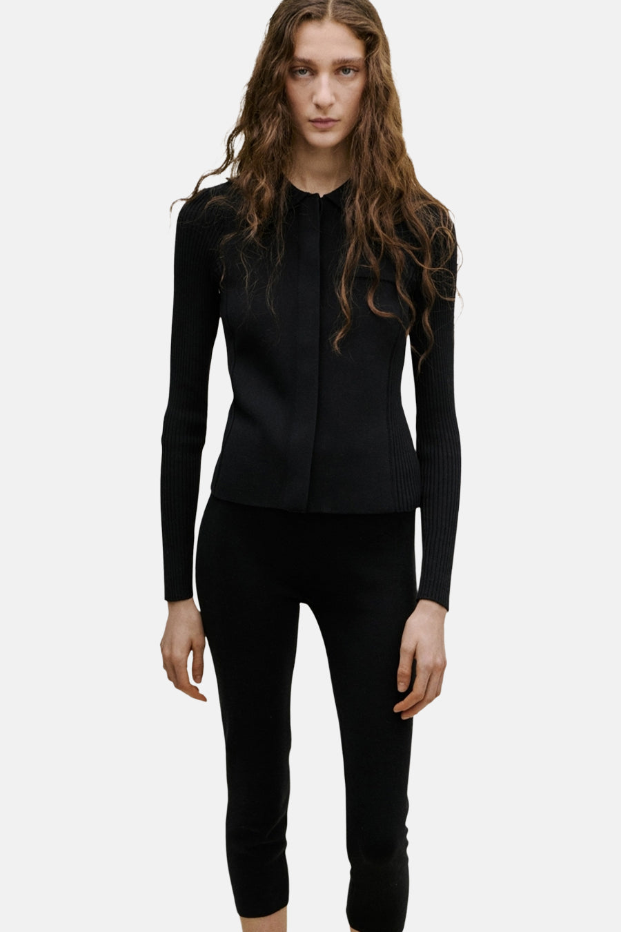 Gilet noir de MANGO, vue arrière, combiné avec un pantalon noir et des talons ouverts.