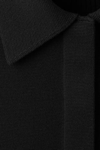 Gilet noir de MANGO, avec une texture côtelée et un détail de col classique.