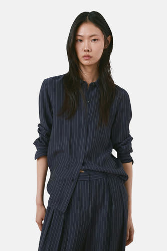 Pantalon bleu MANGO à rayures verticales et plis, assorti à un chemisier rayé assorti.