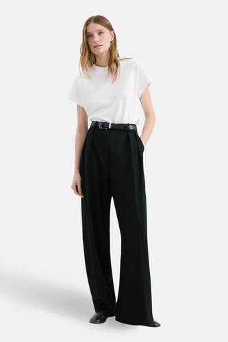 Wit hemd met lange mouwen van MANGO, gedragen met een zwarte broek met hoge taille en riem.
