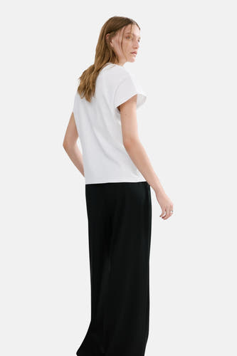 Wit hemd met lange mouwen van MANGO, met effen zwarte broek en nonchalant kapsel.
