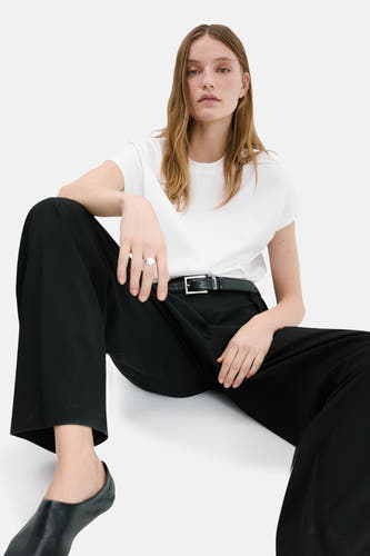 Wit hemd met lange mouwen van MANGO, gedragen met zwarte pantalon en riem in een casual zittende pose.
