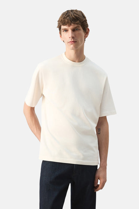 Ecru T-shirt met korte mouwen van MANGO, gedragen met een donkere jeansbroek.