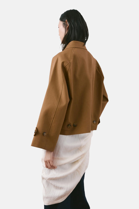 Bruine korte jas van MANGO, met lange mouwen en knoopdetails aan de onderkant, op een model van achteren gezien.
