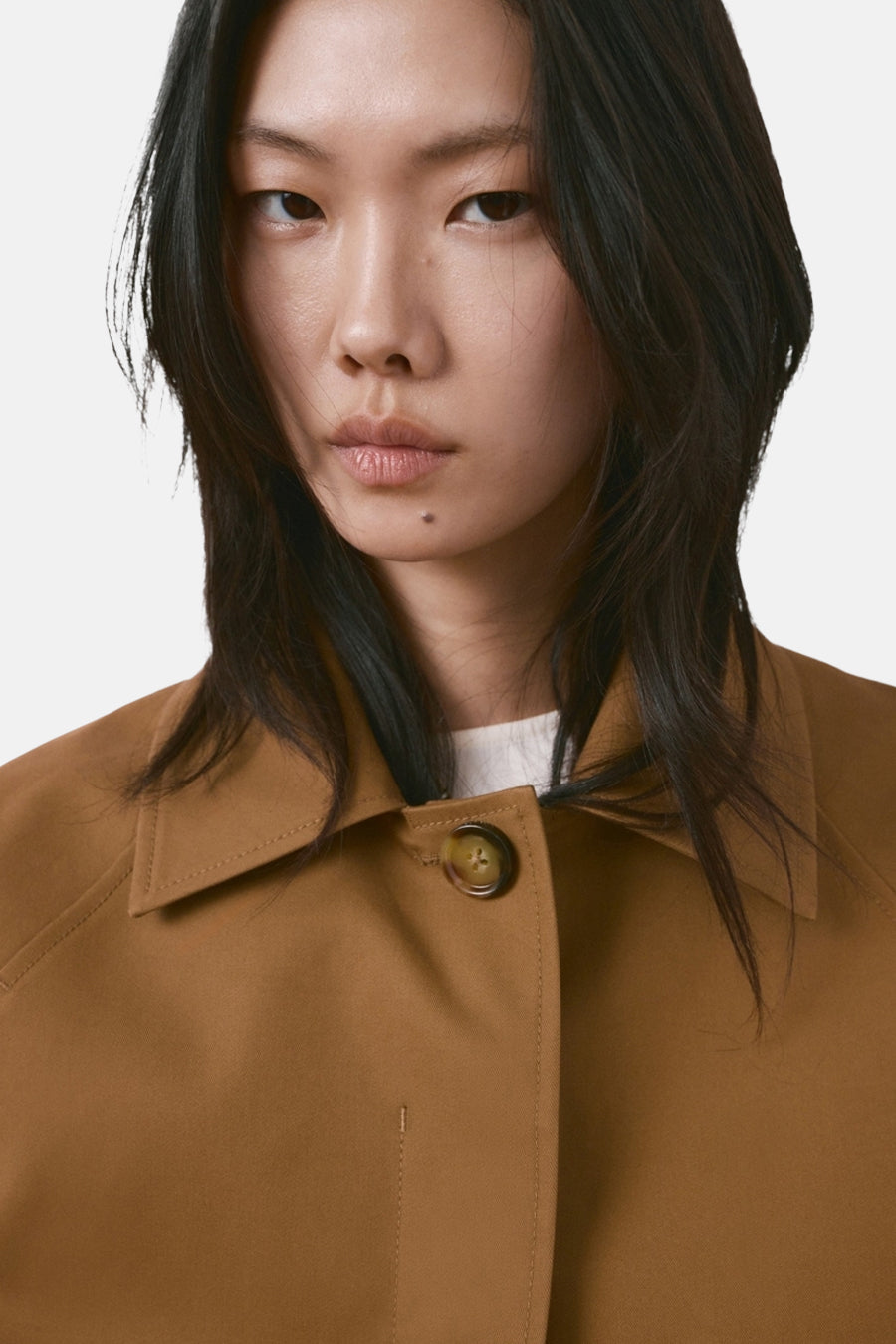 Manteau court marron de MANGO, à manches longues et avec un col, sur fond blanc.