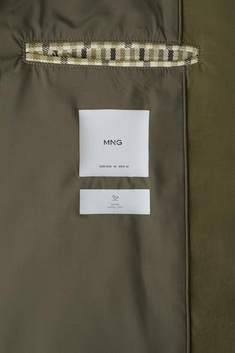 Veste courte marron de MANGO, avec une étiquette et un détail à carreaux écossais à l'intérieur.
