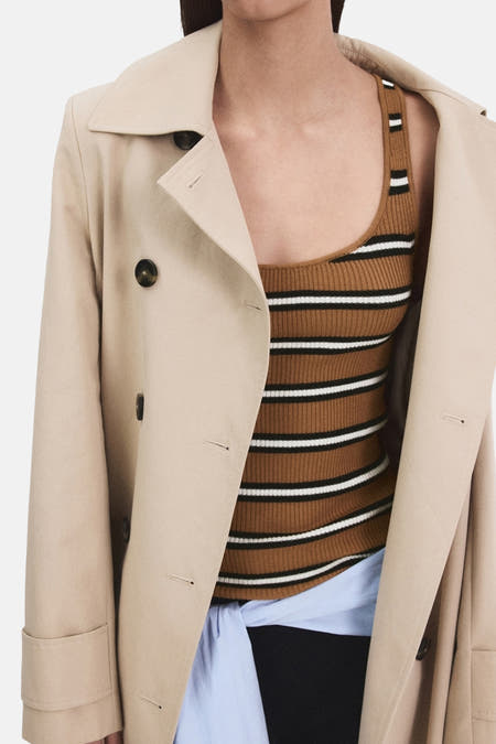 Débardeur multicolore de MANGO à rayures horizontales, porté sous un trench-coat beige et une chemise bleue.