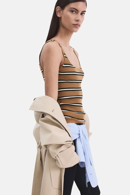 Multikleurige singlet van MANGO met horizontale strepen, gedragen onder een beige trenchcoat en een blauw overhemd.