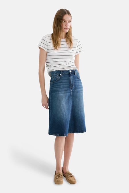 T-shirt blanc à rayures à manches courtes de MANGO, porté avec une jupe en jean bleue et des chaussures marron.