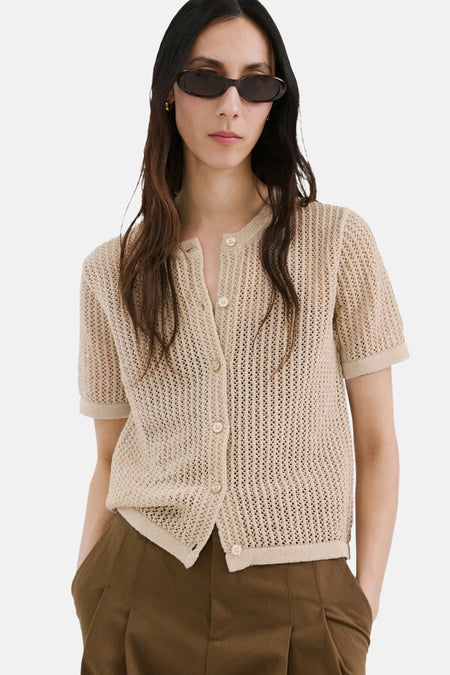 Bruin gilet van MANGO, met korte mouwen en een opengebreide textuur, gedragen met een bruine broek.
