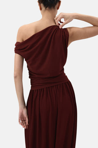 Mouwloze bruine top van MANGO, met gedrapeerde details en een one-shoulder model, gezien van achteren.