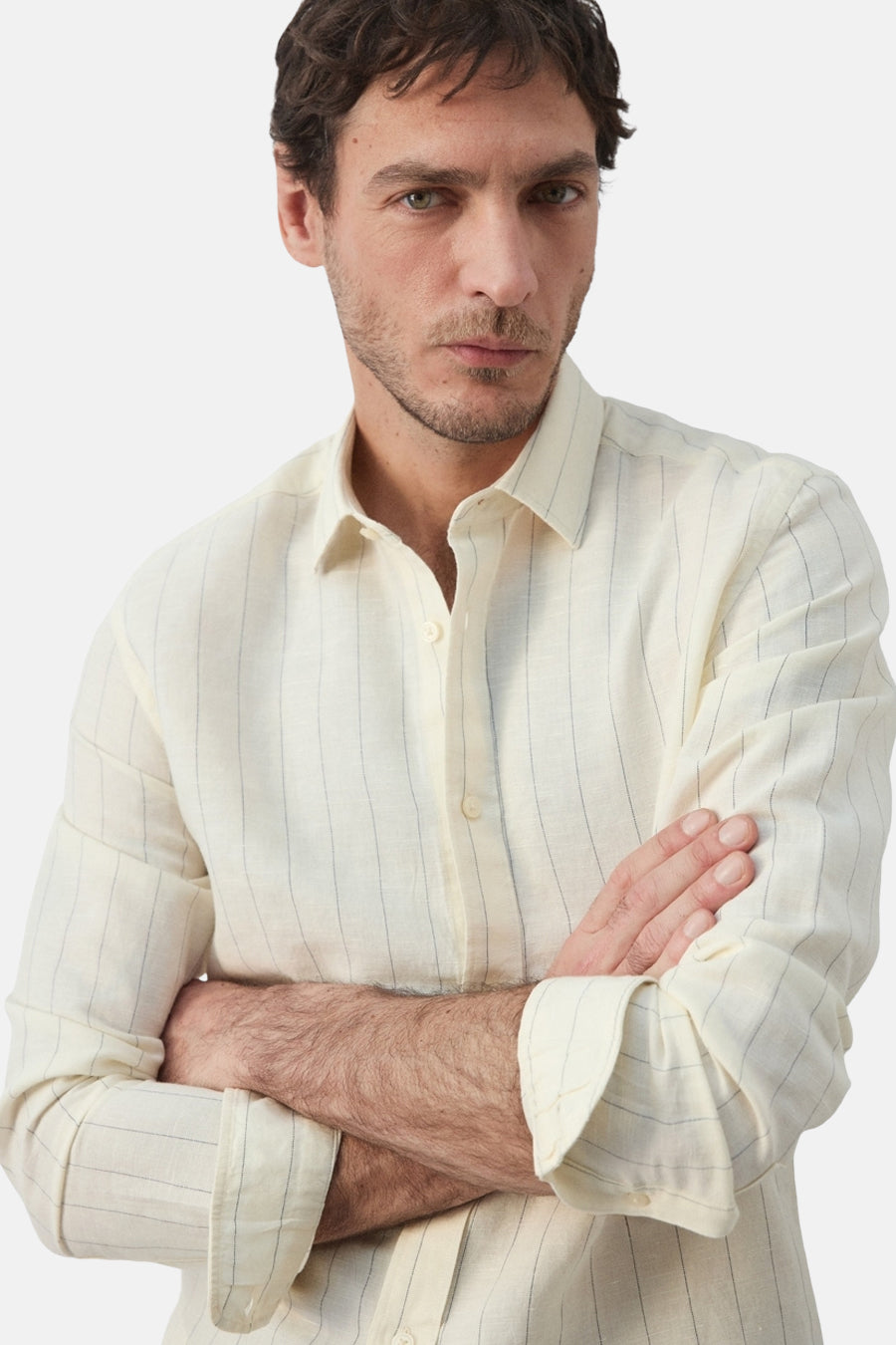 Chemise écru à manches longues de MANGO, avec un motif rayé et des bras croisés.