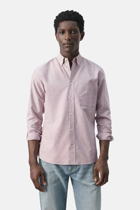 Roze gestreept overhemd van MANGO, met lange mouwen en een borstzakje, gedragen met een blauwe jeans.
