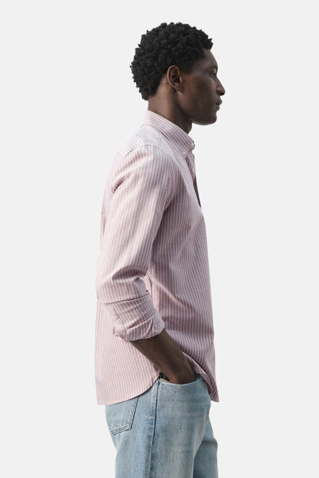 Roze overhemd van MANGO met lange mouwen en fijne verticale strepen, zijwaarts weergegeven, gecombineerd met blauwe jeans.

