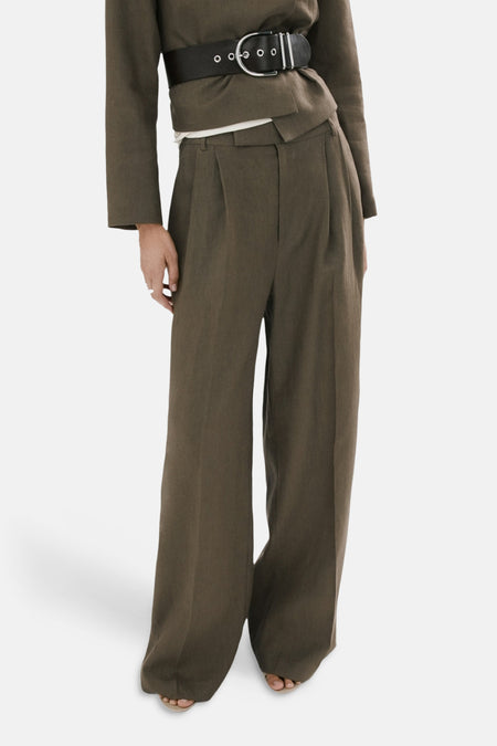 Khakikleurige broek van MANGO met wijde pijpen en plooien, gedragen met bijpassend jasje en zwarte riem.