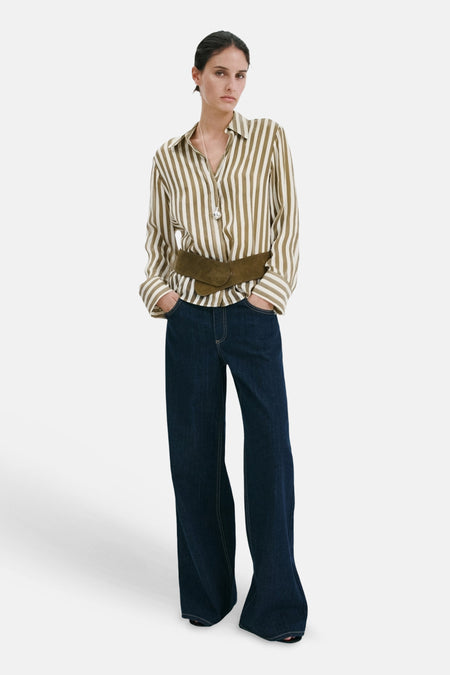 Chemise rayée blanc et vert olive de MANGO, stylisée avec un jean foncé et une large ceinture aspect daim.