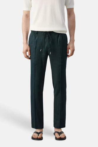 Donkergroene broek van MANGO met trekkoord, gedragen met een wit shirt en sandalen.